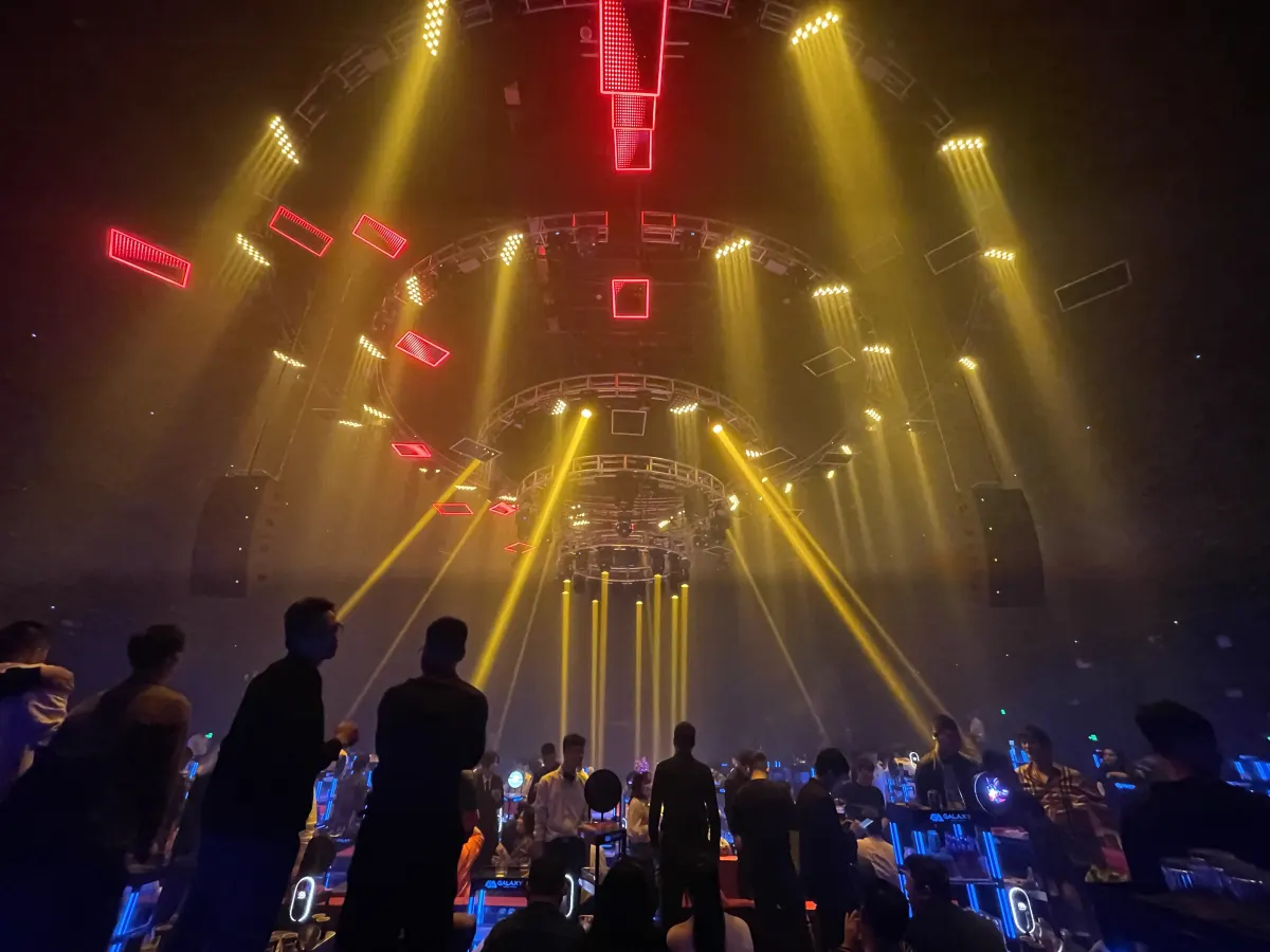 Yellow beams from a kinetic rig over a concert crowd