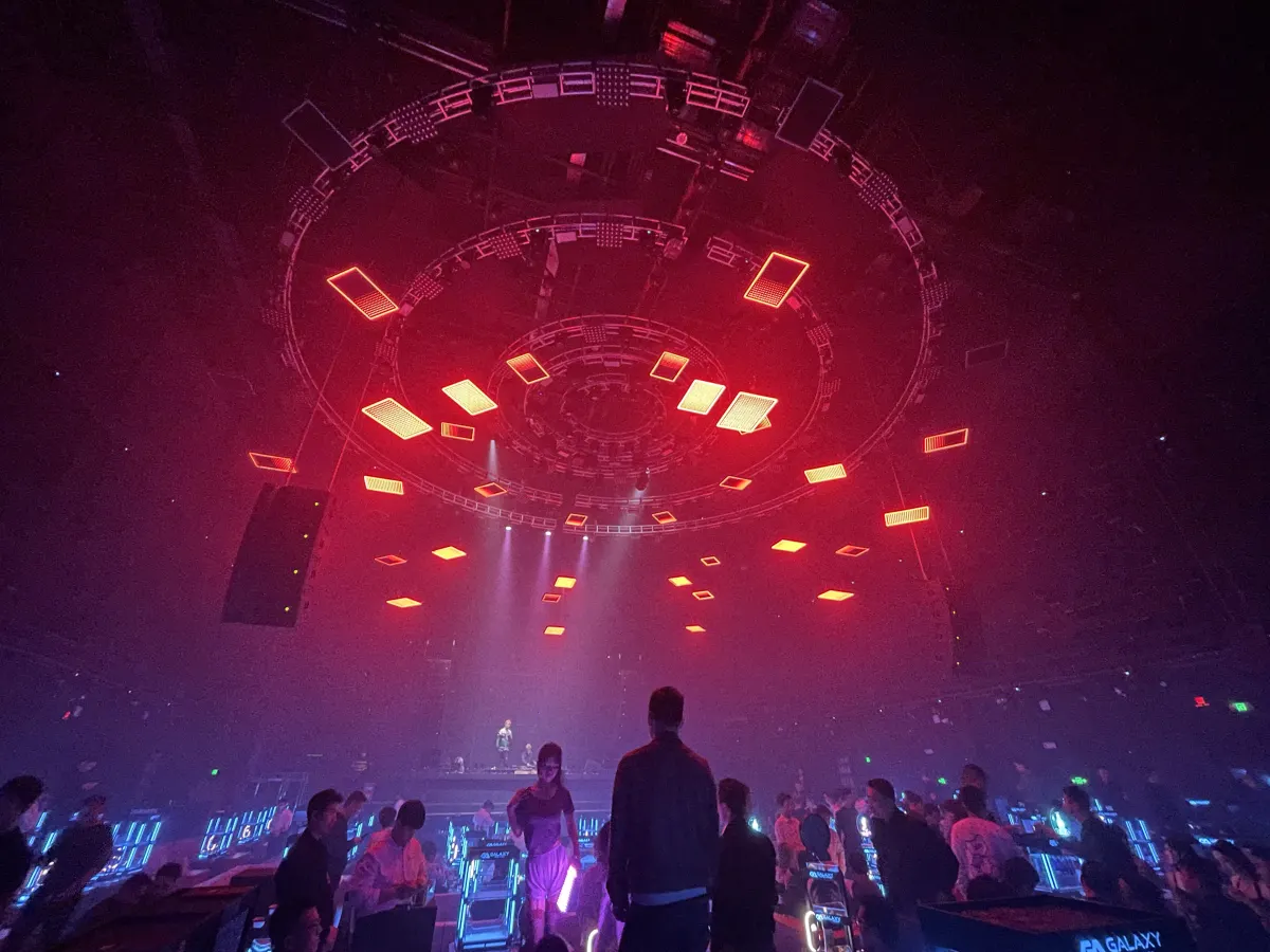 Red kinetic chandelier above a club crowd